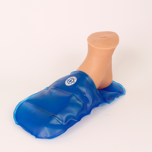 Pé utilizando bolsa térmica em formato de pantufa de gel HOTCOLD, na cor predominante azul, com a logo da Ortho Pauher, em cor branca centralizado na parte superior da pantufa.