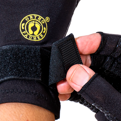 A imagem mostra detalhes do fechamento do velcro da luva, em cima do velcro contem a logo da Ortho Pauher em amarelo. A luva é preta.