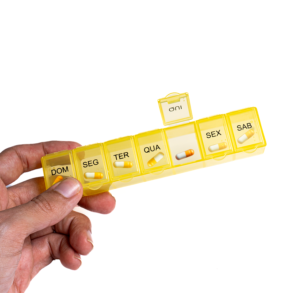 Pessoa segurando um organizador de pílulas e comprimidos, cor amarela. 