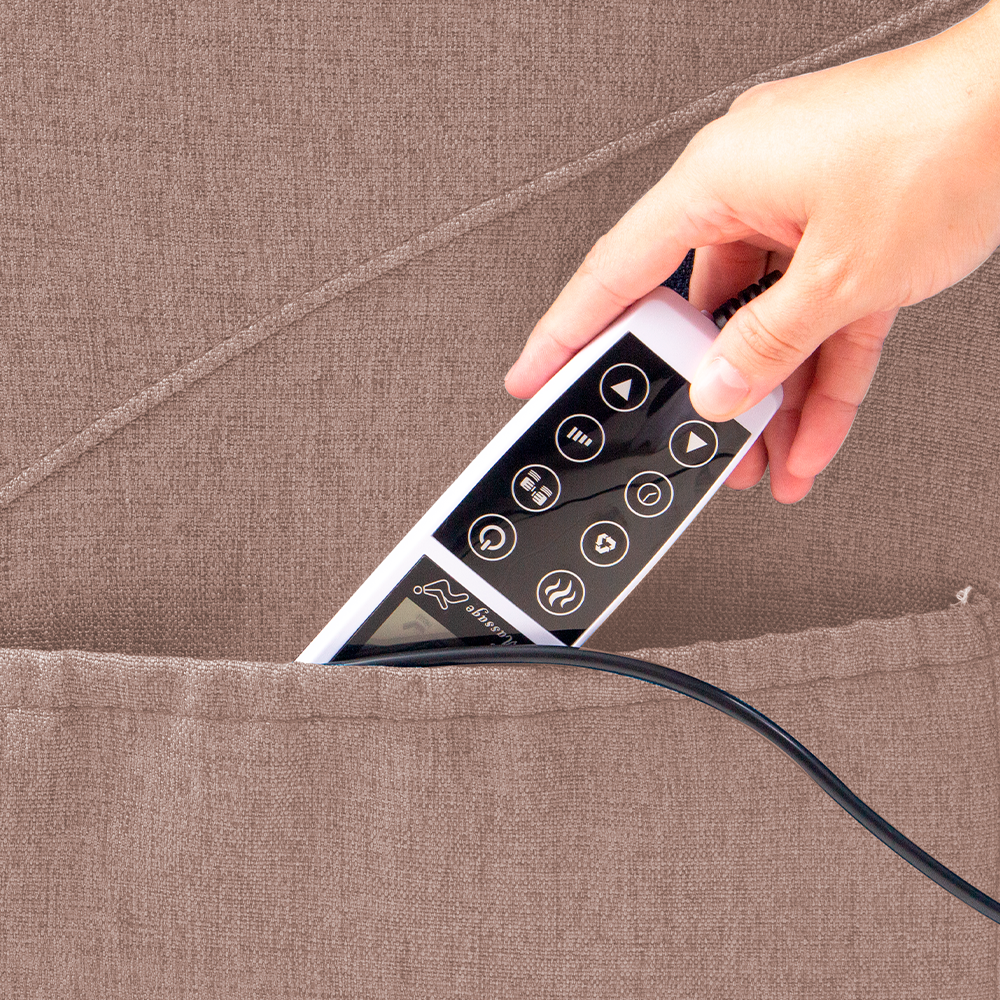 A imagem mostra uma mão retirando o controle do bolso lateral da poltrona. A poltrona é na cor marrom claro.