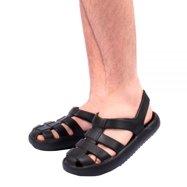 Pessoa utilizando a sandália ortopédica com solado anatômico e base larga, espuma macia com ação anti-impacto, fechamento parcial na parte superior para maior firmeza e solado espesso de quase 4 cm que distribui o peso, proporcionando conforto e alívio das dores plantares.  Sandália cor preta.