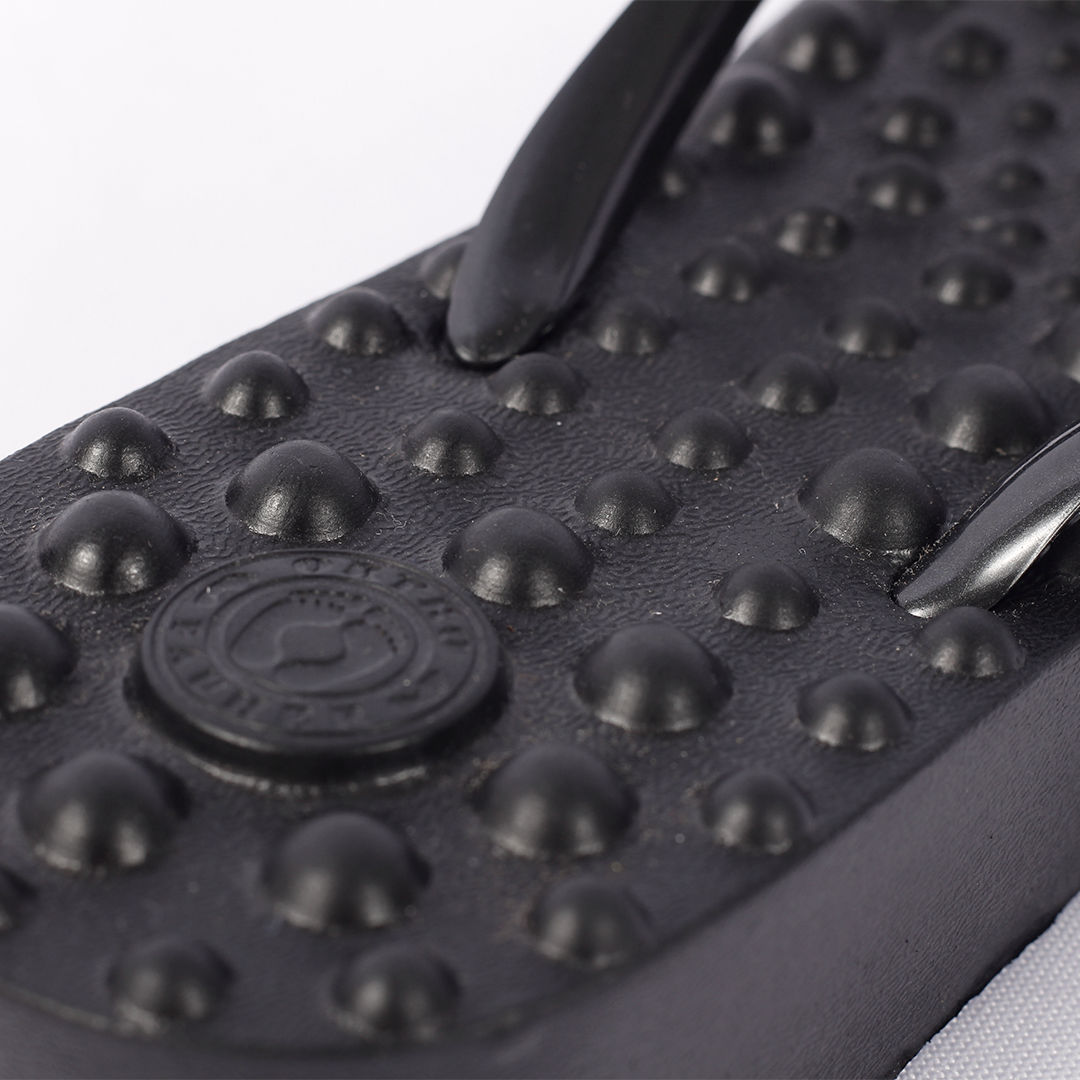 Sandália Ortopédica Flyfeet Relax, cor preta,  mostrando em destaque a superfície com protuberâncias em alto relevo, projetada para ativar a circulação e estimular as terminações nervosas da planta dos pés, promovendo relaxamento e alívio da dor. 