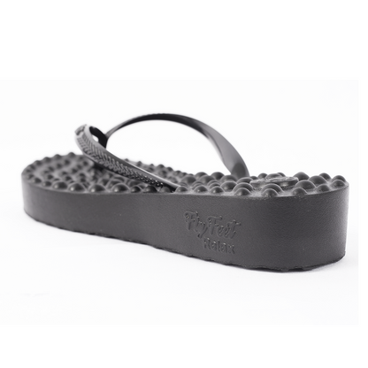 Sandália Ortopédica Flyfeet Relax, cor preta, com destaque para o salto anabela. É possivel ver superfície com protuberâncias em alto relevo, projetada para ativar a circulação e estimular as terminações nervosas da planta dos pés, promovendo relaxamento e alívio da dor.