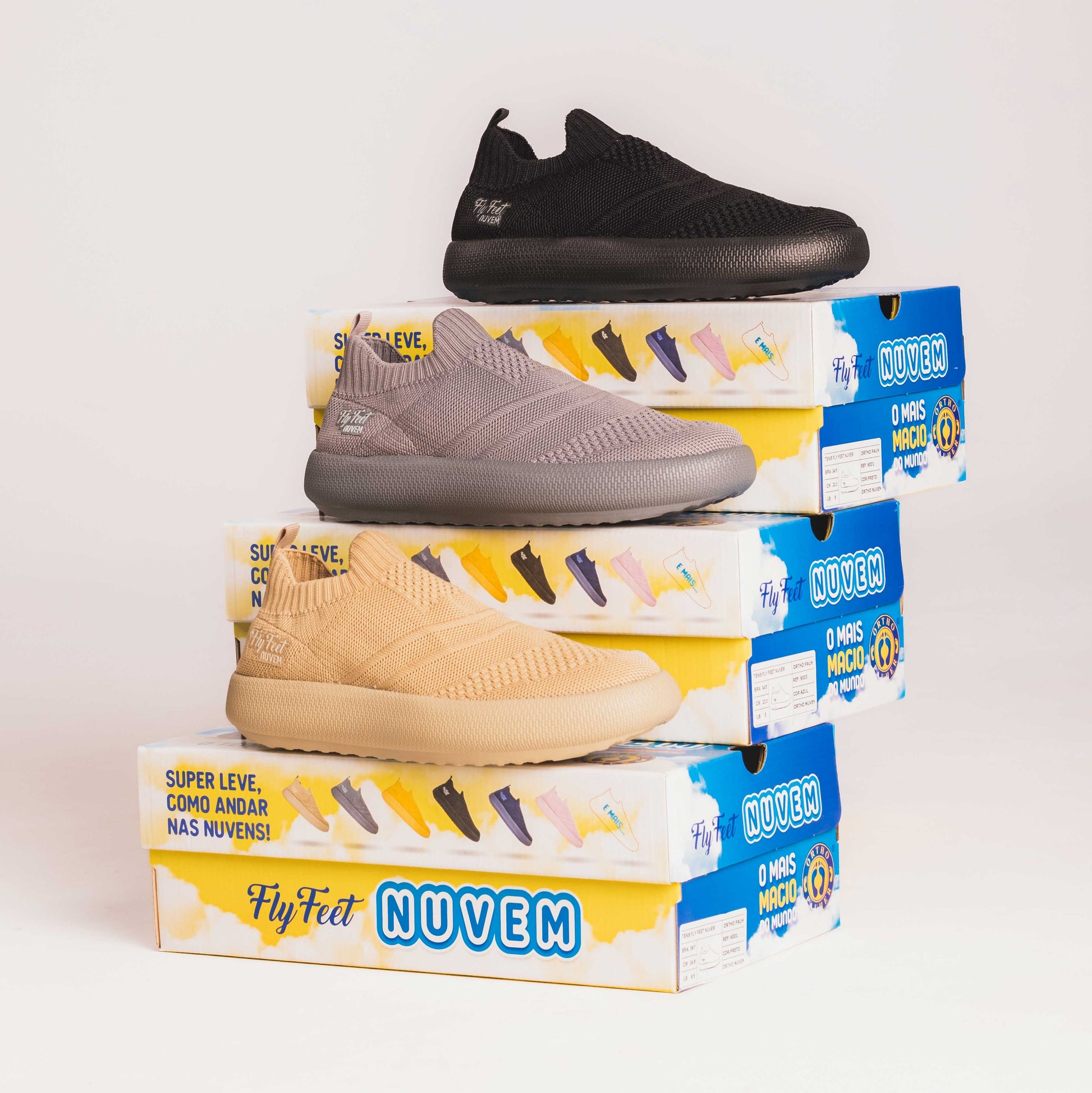 A imagem mostra três caixas empilhadas cada uma com um tênis de cor diferente, sendo um preto, cinza e bege

